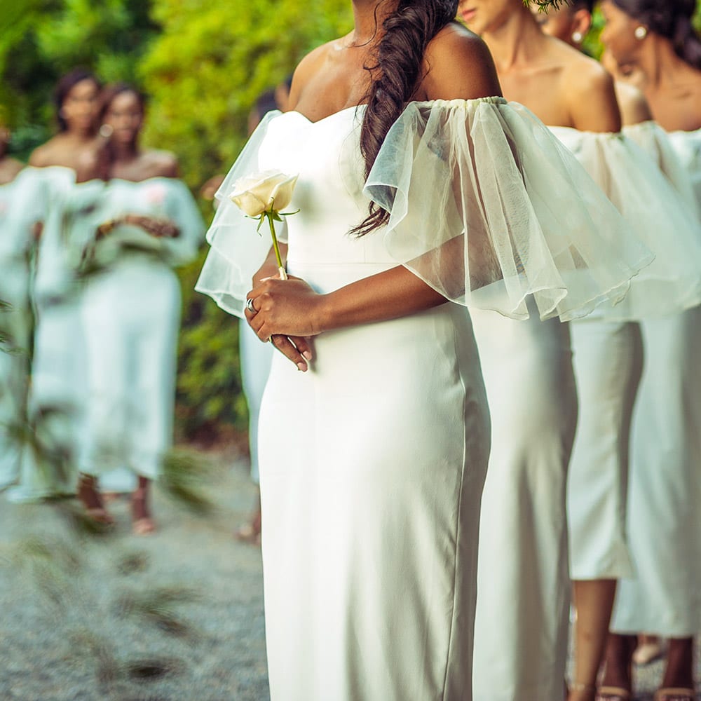 Women wearing white dresses and holding a yellow flower