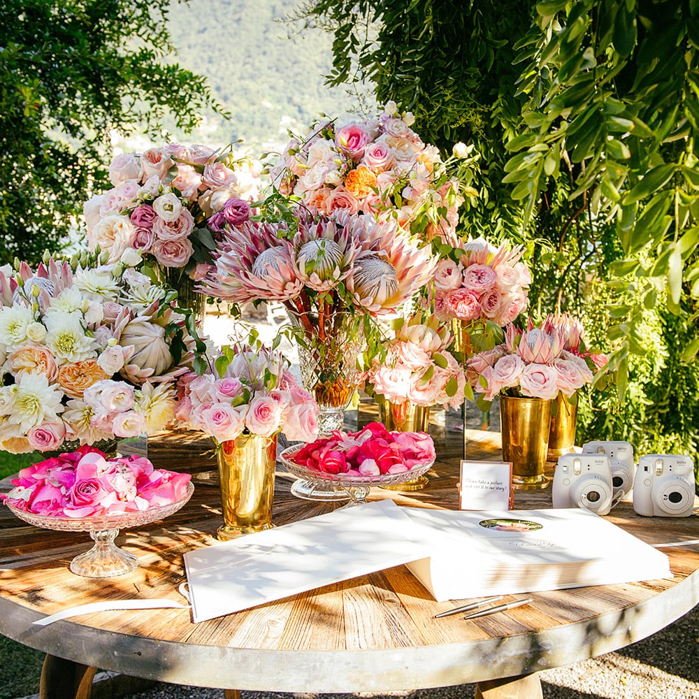 A wooden table decorated with bouquets of pink and white flowers