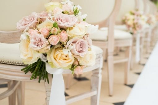 Stunning bouquet of pastel coloured roses tied to a white chair at a luxury wedding in Blenheim Palace