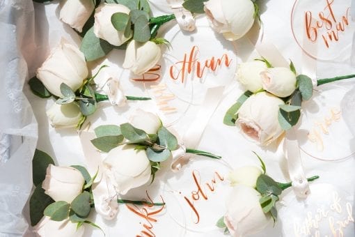 White rose buttonholes and hand calligraphed name tags for a celebrity wedding party
