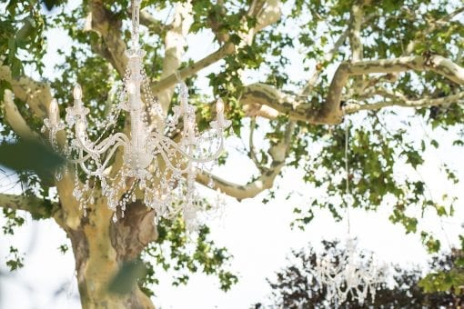 A stunning crystal chandelier hanging in a tree above a luxury destination wedding ceremony in Barcelona