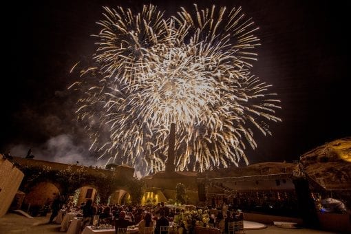 Lavish gold fireworks exploding over evening wedding reception in Greece at a large scale and high budget wedding