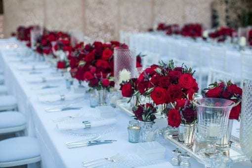 Luxury dinner table styled with stunning red roses, crystal vases, silver trays at a luxury destination wedding
