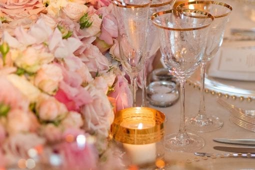 Pink and cream floral centrepiece with gold etched glassware, charger plates and candles at a luxury wedding at Blenheim Palace