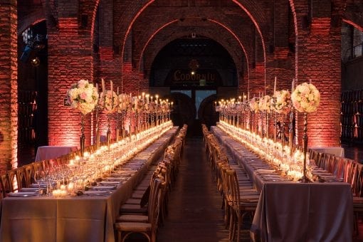 Lavish wedding with two long tables, candlelight running the full length of a cellar at Codorniu for a destination wedding in Spain