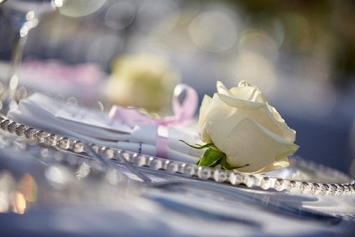 Delicate cream roses on a silver charger plates at a luxury wedding reception in Oxfordshire