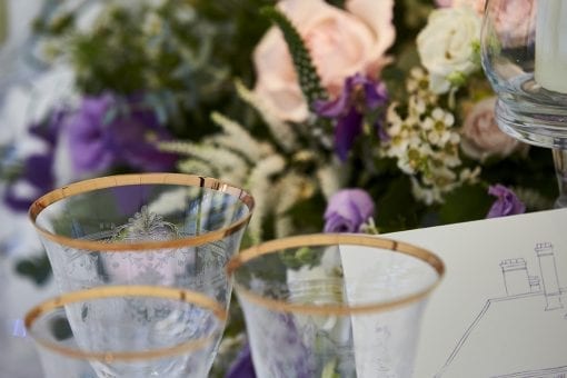 Gold rimmed wine glasses with a floral table centrepiece