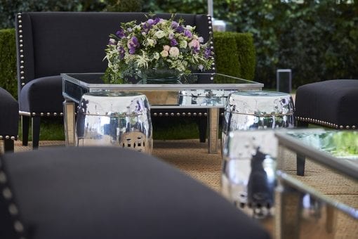 Reception seating with back and silver styling with purple and cream flowers