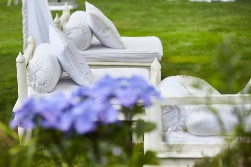 Indian inspired soft seating with white cushions under a white Raj tent at a private wedding