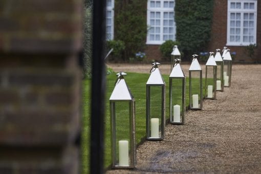 Tall silver lanterns with pillar candles lining the driveway of a private estate for a luxury wedding