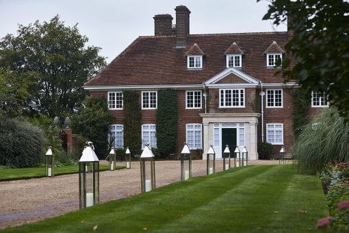 Breathtaking private estate wedding entrance lined with tall lanterns for a wedding reception