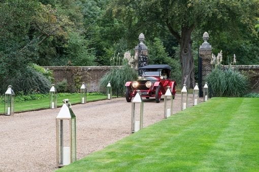 Bride and groom arriving at a private estate lined with tall candles for a luxury countryside wedding