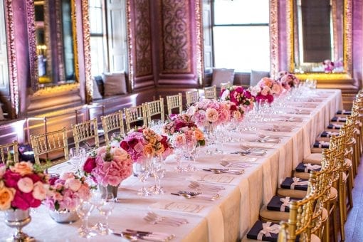 Beautiful table and chairs set for dinner at with stunning pink floral centrepieces at Little Banqueting House, at Hampton Court Palace