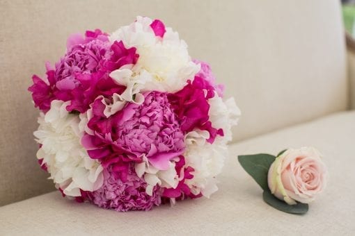 Bright pink and white peonies in bridal bouquet with a pink rose button hole