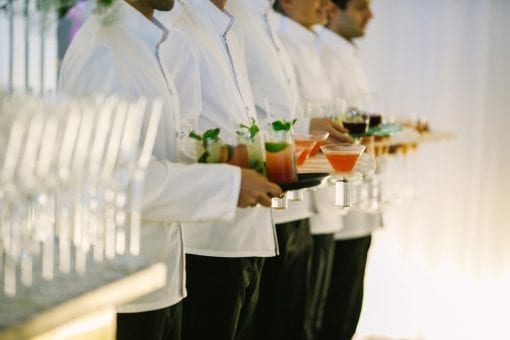 Smart waiters in white with bespoke cocktails and champagne ready for guests to arrive at a corporate brand event