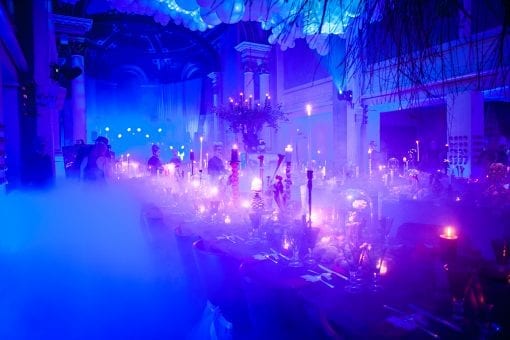 A smokey room full of party haze with two long tables set for dinner at a surrealist party in One Marylebone