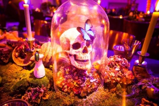 A private surrealist themed party at One Marylebone in London with a collection of quirky table decorations including a skull in a bell jar, flowers and candles working with top florist Nikki Tibbles