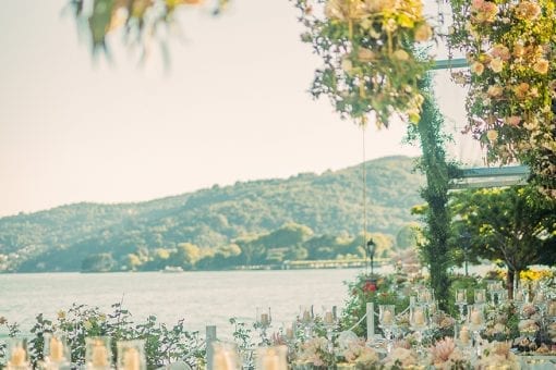 Luxury wedding with elegant tables set for dinner and large floral chandeliers at Villa Pizzo in Lake Como, Italy