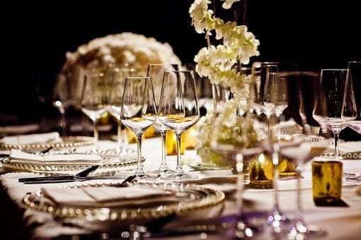 Wine glasses and cutlery on a table with white orchid flowers for a white wedding for Nigerian couple