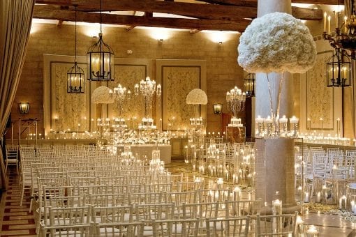 Stunning candle lit luxury wedding ceremony with white chairs and large floral arrangements