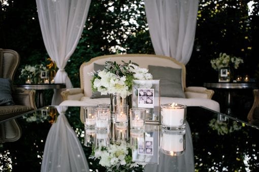 Beautiful white draping under a Raj tent at a private event with soft French style furniture and mirror top table