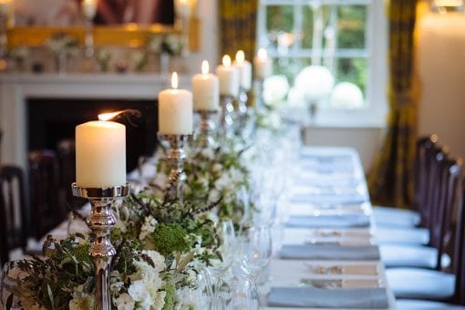A beautiful long table with green and white floral runner and pillar candles for a lavish private event
