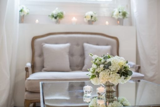 Pretty white and green flower arrangements on mirror top tables with french style soft seating at One Marylebone