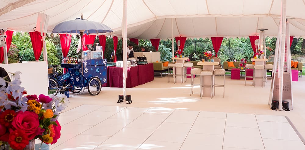 Bespoke marquee set for a luxury Indian wedding with seating area and colourful rickshaw for a Mehndi