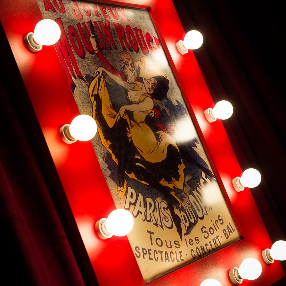 French poster prop of the Moulin Rouge in a red frame with lightbulbs for a Moulin Rouge themed birthday party in London