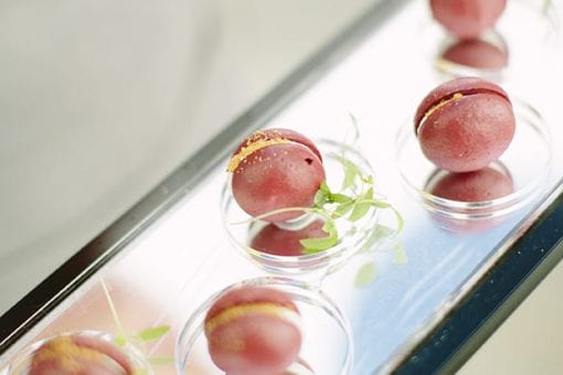 Delicate macaroons on a mirror canape tray at a private birthday party
