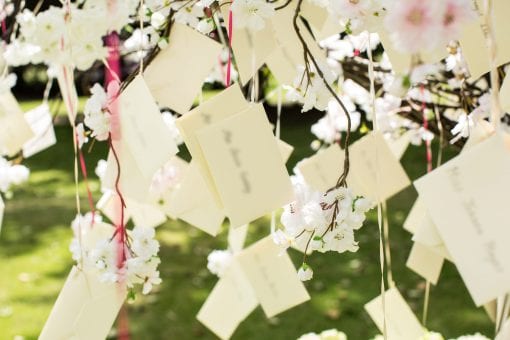 Hand written escort cards suspended from cherry tree at luxury wedding in London