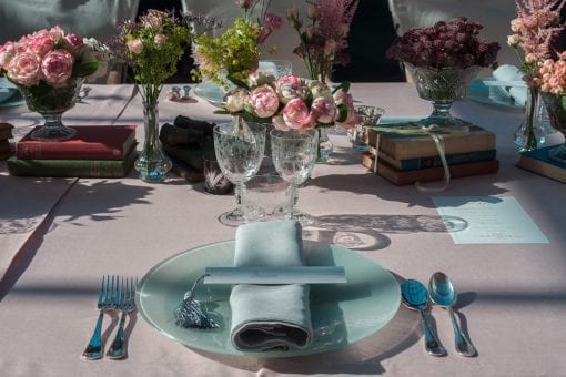 Table setting decorated with a combination of flowers and books for a destination private birthday party in St Tropez, France
