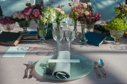 A beautiful vintage styled table set for dinner with roses, books and napkins in St Tropez, France
