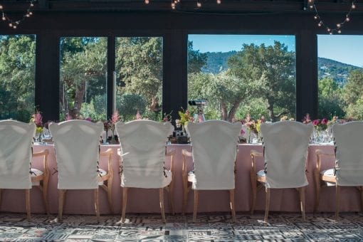 A long table set for dinner, decorated with fresh flowers and books overlooking a scenic view of St Tropez