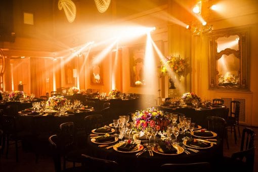 Round tables set for a lavish birthday party with stunning flowers and lighting design