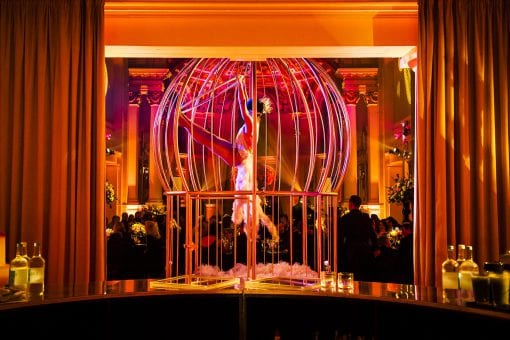 Roxy Velvet performing aerial acrobats in birdcage wearing feathers at a luxury birthday party in One Marylebone