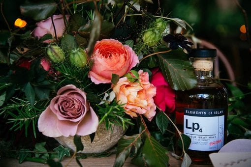 Bouquet of English garden roses next to a bottle of Scotch whisky at a luxury wedding in the English countryside