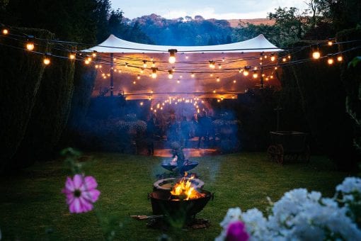 Festoon lighting and fire pits lighting the way to the afterparty under a stretch at a private estate for a luxury wedding