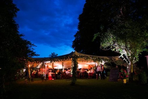 A rustic luxury wedding under a stretch tent at night with florals and candle lit lighting at a private estate