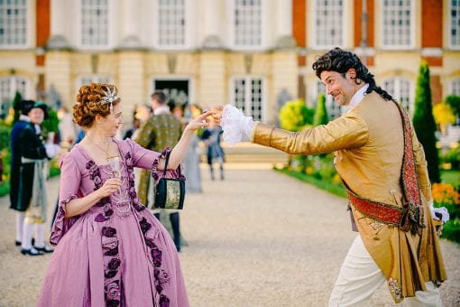 Guests in period costume for a Marie Antoinette styled event at a champagne drinks reception in Hampton Court Palace's Privy Garden