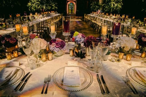 Stunning tablescape at a luxury birthday dinner styled with white and purple flowers and candles in the Great Hall at Hampton Court Palace
