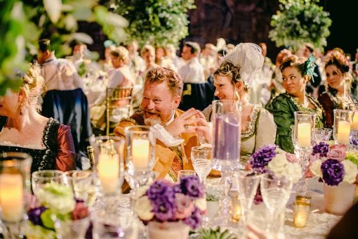 Guests dressed in costume sat at dinner amongst impressive tablescape at Hampton Court Palace