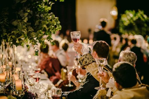 Birthday party guests in period costume toasting the birthday host in the Great Hall at Hampton Court Palace