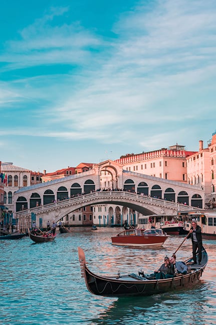 Boats and gondolas passing under the Rialto Bridge in Venice, Italy for a luxury destination wedding