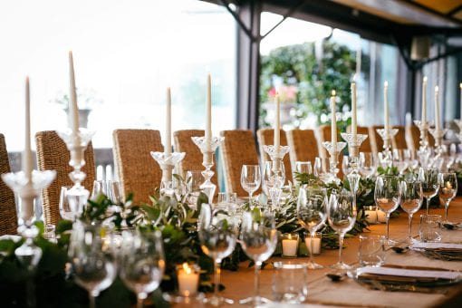 Nigerian rehearsal dinner, with an elegant wedding table with candles and green foliage.