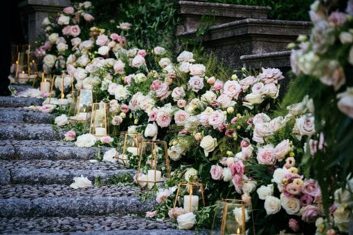 Cobbled stone steps styled for a wedding ceremony with elegant ceremony aisle arrangements of fresh roses and flowers and stylish gold rimmed candle holders for luxury destination wedding at Villa Pizzo, in Lake Como, Italy
