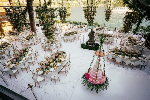 Beautiful tables set for dinner at a wedding reception with decorative flowers overlooking top wedding destination Lake Como