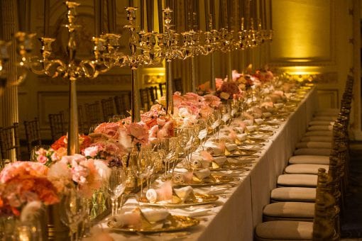 A high end dinner setting with opulent gold candles and pretty floral runner for a world class celebrity