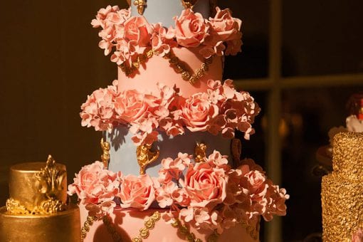 A large tiered cake decorated with intricate floral and gold icing