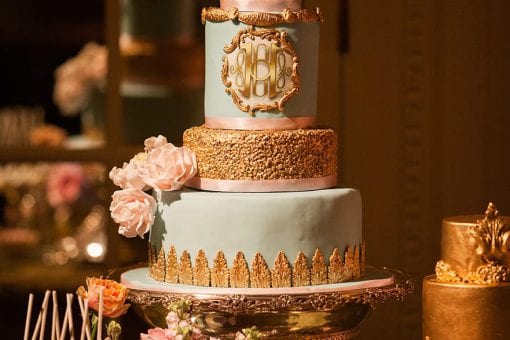 A gold decorated tiered cake surrounded by flowers, lollipops and cupcakes for a Moulin Rouge party at the Mandarin Oriental